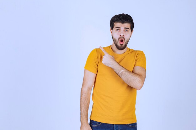 Hombre con camisa amarilla mostrando algo a la izquierda.