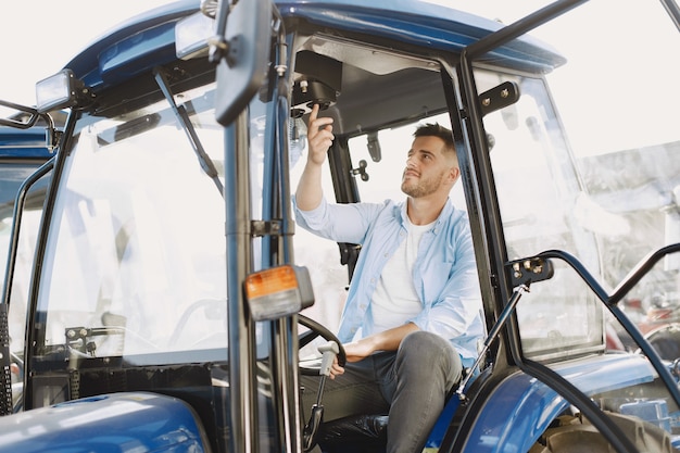 Hombre con camisa azul. Chico en un tractor. Maquinaria de agricultura.