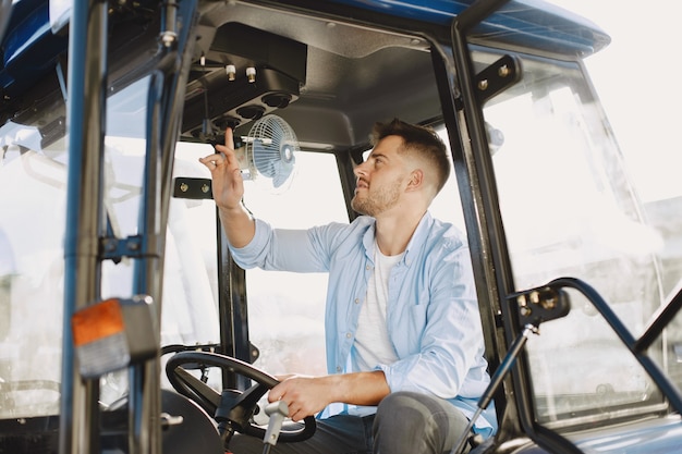 Hombre con camisa azul. Chico en un tractor. Maquinaria de agricultura.