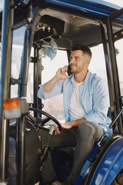 Hombre con camisa azul. Chico en un tractor. Maquinaria de agricultura.