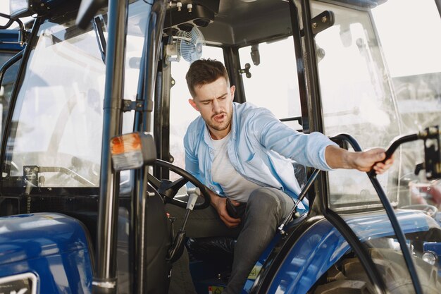 Hombre con camisa azul. Chico en un tractor. Maquinaria de agricultura.
