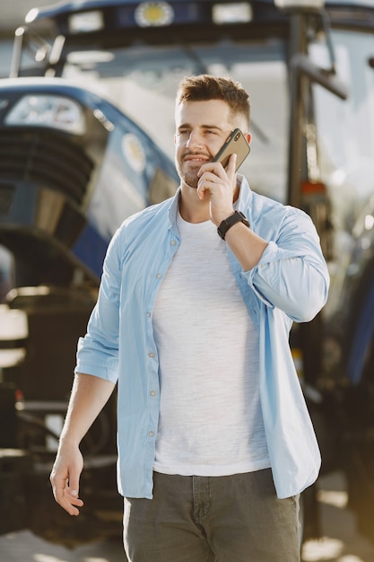 Hombre con camisa azul. Chico en un tractor. Maquinaria de agricultura.