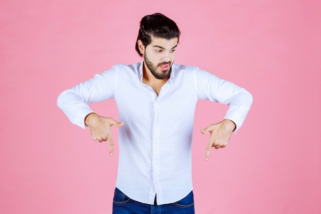 Hombre con camisa blanca apuntando hacia abajo.