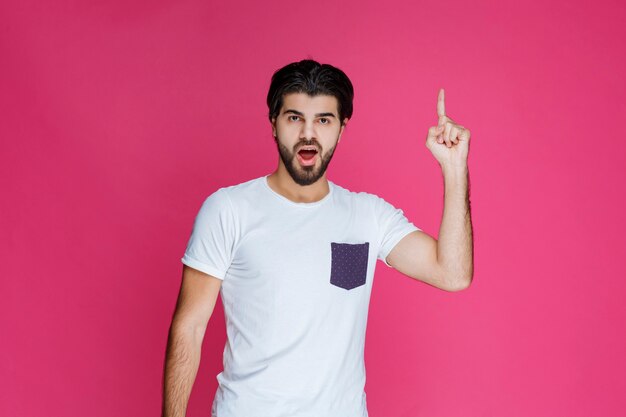 Hombre con camisa blanca apuntando a algo arriba.