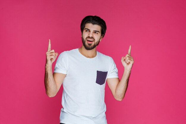 Hombre con camisa blanca apuntando a algo arriba.