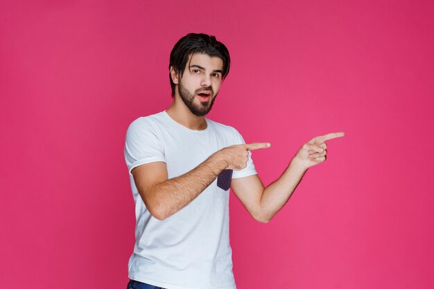 Hombre con camisa blanca apuntando a algún lugar y presentando a alguien o simplemente mostrando la dirección.