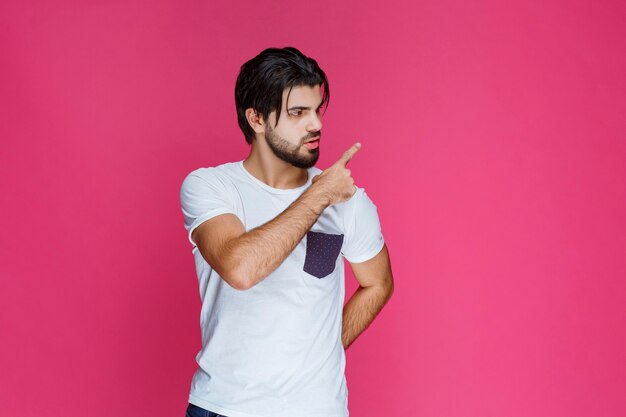 Hombre con camisa blanca apuntando a algún lugar y presentando a alguien o simplemente mostrando la dirección.