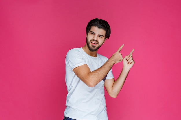 Hombre con camisa blanca apuntando a algún lugar y presentando a alguien o simplemente mostrando la dirección.