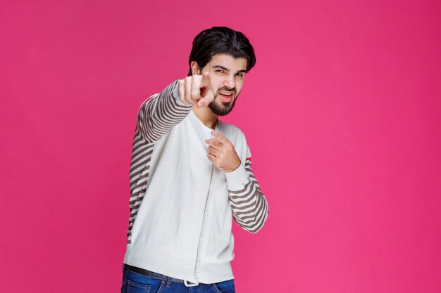 Hombre con camisa blanca apuntando a algún lugar y presentando a alguien o simplemente mostrando la dirección.