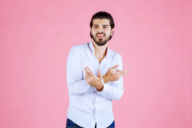 Hombre con camisa blanca apuntando a ambos lados.