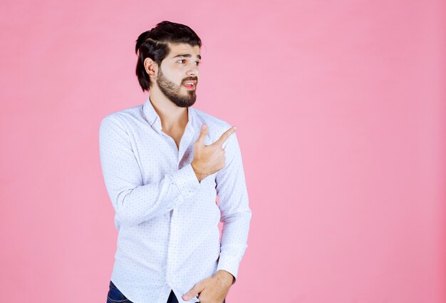 Hombre con camisa blanca apuntando hacia el lado derecho.