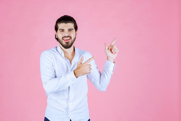 Hombre con camisa blanca apuntando hacia el lado derecho.