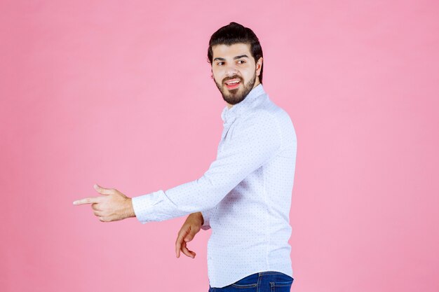 Hombre con camisa blanca apuntando hacia el lado izquierdo.