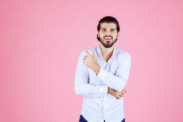 Hombre con camisa blanca apuntando hacia el lado izquierdo.