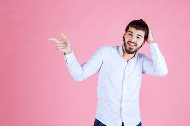 Hombre con camisa blanca apuntando hacia el lado izquierdo.