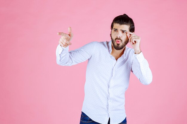 Hombre con camisa blanca apuntando hacia el lado izquierdo.