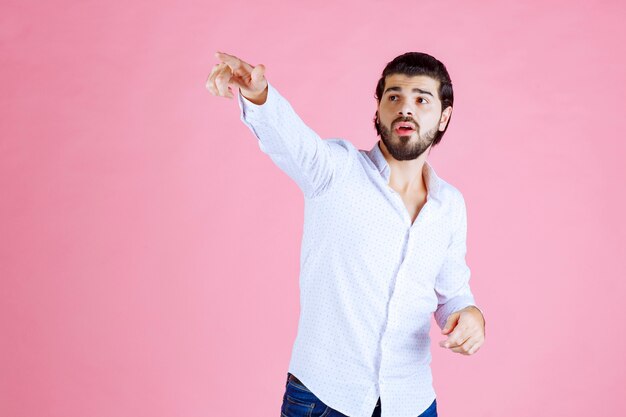 Hombre con camisa blanca apuntando hacia el lado izquierdo.