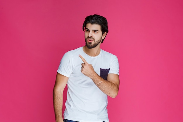 Hombre con camisa blanca apuntando y presentando algo por encima de su cabeza.