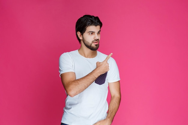 Hombre con camisa blanca apuntando y presentando algo en el lado derecho.