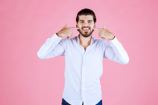 Foto gratuita hombre con camisa blanca apuntando a su sonrisa.