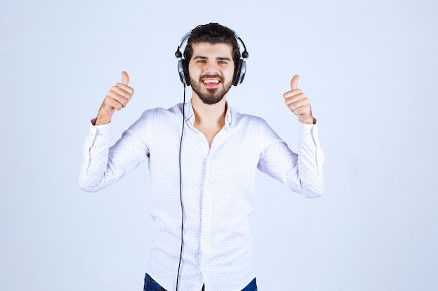 Hombre de camisa blanca con audífonos y disfrutando de la música