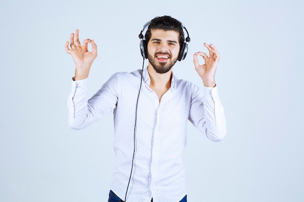 Hombre de camisa blanca con audífonos y disfrutando de la música