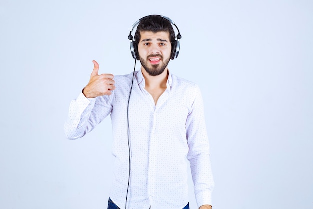 Hombre de camisa blanca con audífonos y disfrutando de la música