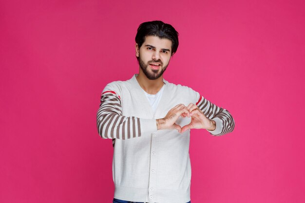 Hombre con camisa blanca enviando amor.