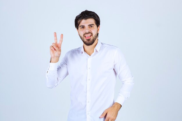 Hombre con camisa blanca enviando mensaje de paz y amistad