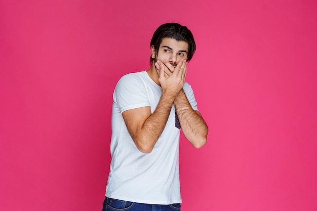 Foto gratuita el hombre con camisa blanca hace señas para guardar silencio y dejar de hablar.