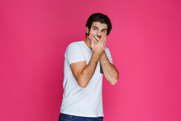 El hombre con camisa blanca hace señas para guardar silencio y dejar de hablar.