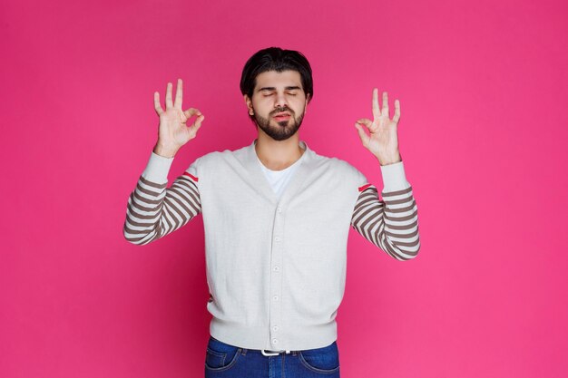 Hombre con una camisa blanca haciendo plena satisfacción o signo de la mano de meditación.