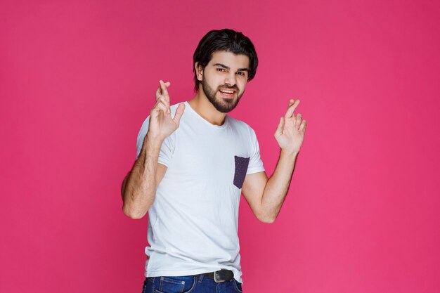 Hombre con camisa blanca haciendo signo de cruz de mano.