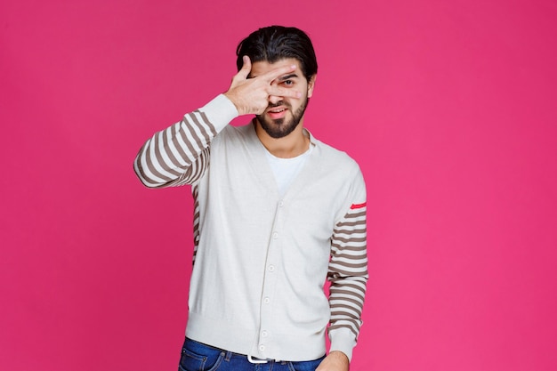 Hombre con camisa blanca haciendo el signo de la paz.