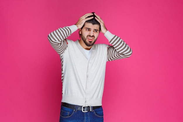 Foto gratuita el hombre con camisa blanca se lleva la mano a la cabeza como si estuviera pensando profundamente y tratando de recordar