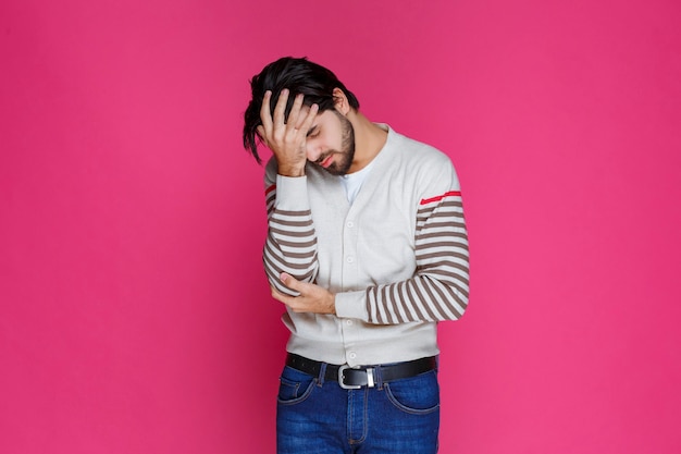 Foto gratuita el hombre con camisa blanca se lleva la mano a la cabeza como si estuviera pensando profundamente y tratando de recordar