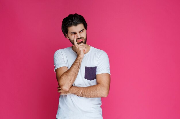 Hombre de camisa blanca llevándose la mano a la cara y pensando.