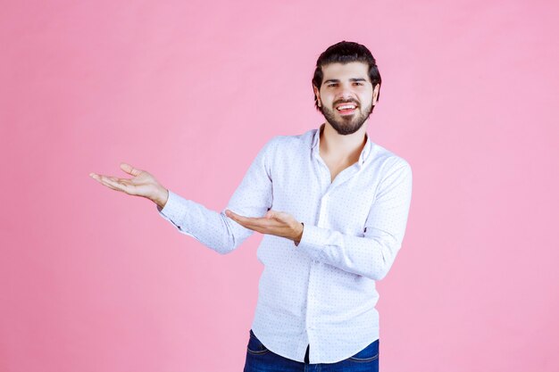 Hombre con camisa blanca mostrando algo en la mano.