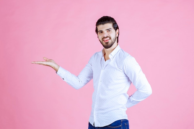 Hombre con camisa blanca mostrando algo en la mano.