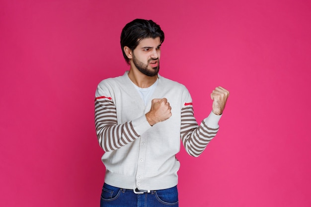 Hombre con camisa blanca mostrando los músculos del puño y bíceps.