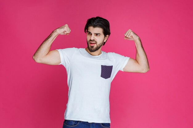 Hombre con camisa blanca mostrando los músculos del puño y bíceps.