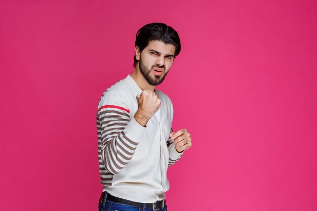 Hombre con camisa blanca mostrando sus puños y poder.