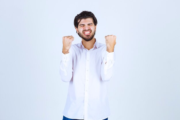 Hombre con camisa blanca mostrando sus puños y sintiéndose exitoso