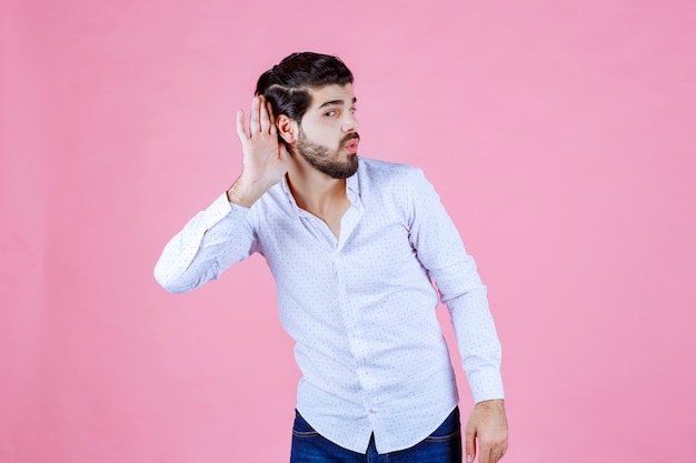 El hombre con una camisa blanca no puede oír bien.