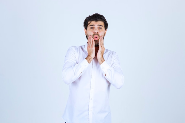 Foto gratuita el hombre con una camisa blanca parece confundido y perdido