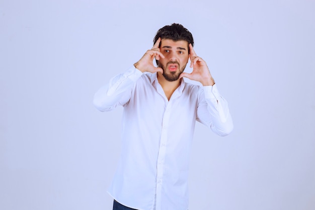 El hombre con camisa blanca parece somnoliento o triste.