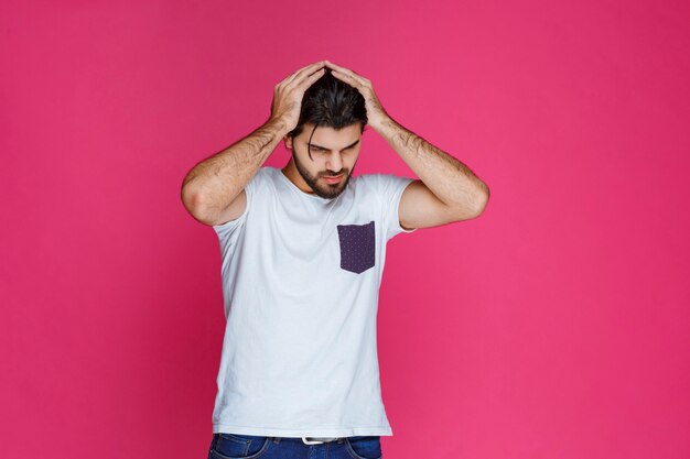 El hombre con camisa blanca parece triste y decepcionado.