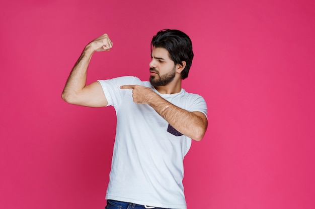 Foto gratuita hombre con camisa blanca que demuestra su poder y los músculos del brazo.