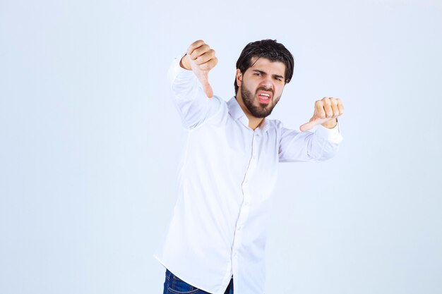 Hombre con una camisa blanca que muestra el pulgar hacia abajo signo