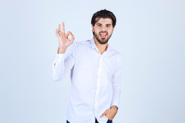 Hombre con una camisa blanca que muestra el signo de la mano de disfrute